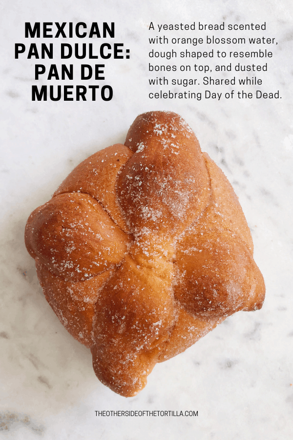 Pan de muerto is a yeasted bread scented with orange blossom water, dough shaped to resemble bones on top, and dusted with sugar. Shared while celebrating Day of the Dead. More pan dulce at theothersideofthetortilla.com.