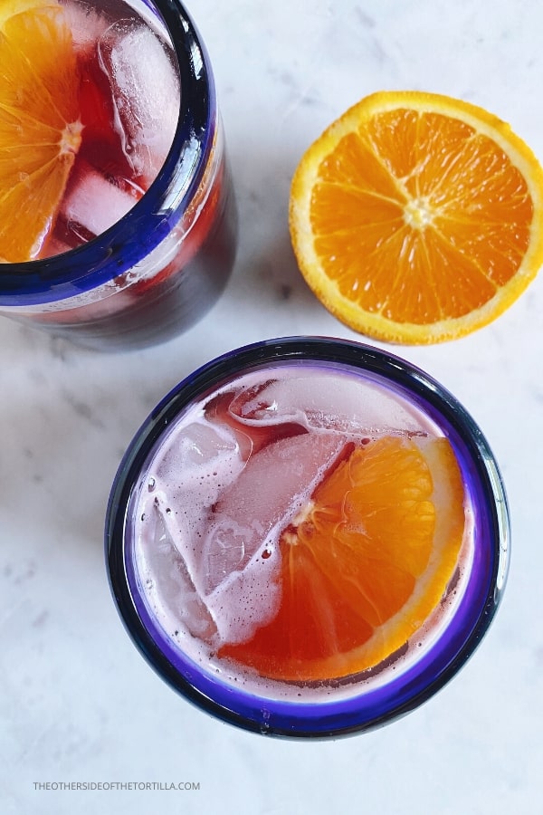 Tinto de verano red wine spritzer cocktail in blue rimmed Mexican glasses with orange slices floating on top