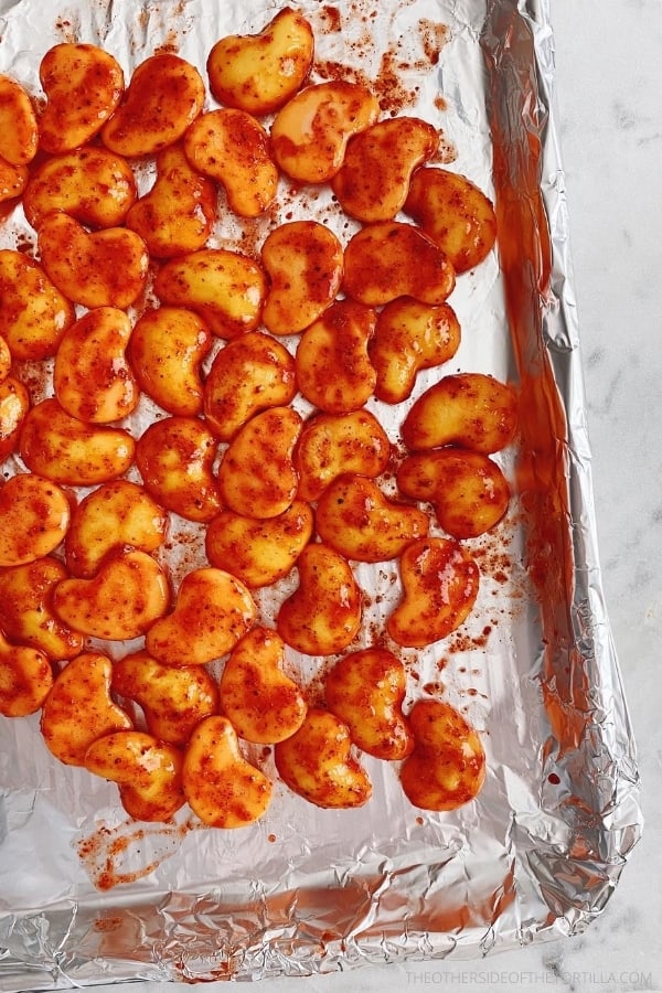 spicy mango gummies drying on a foil-lined quarter sheet pan on top of a white marble surface