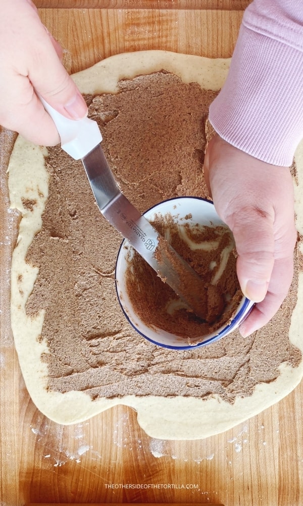 spreading cinnamon roll filling on the dough