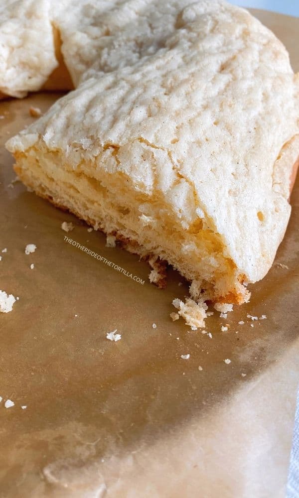 Mexican rosca de reyes with sugar crust on a baking disc over parchment paper